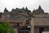 Carcassonne. Pohled z hradeb na střechy města s věžemi citadely v pozadí.